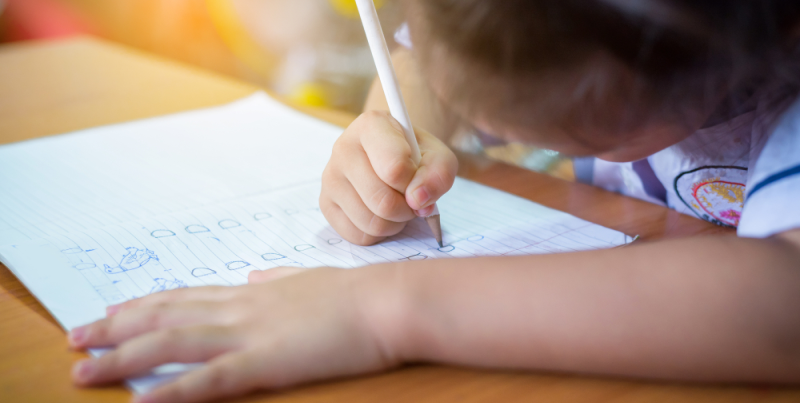 Niña de preescolar realizando actividad de escritura