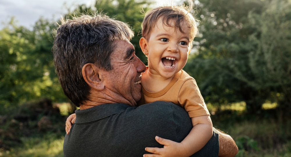 Abuelo carga y cuida a niño pequeño alegre