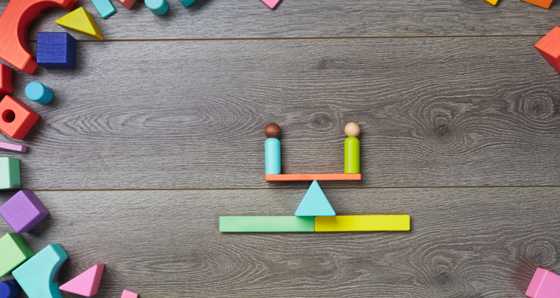 Juguetes de madera en balanza representan igualdad de género infantil
