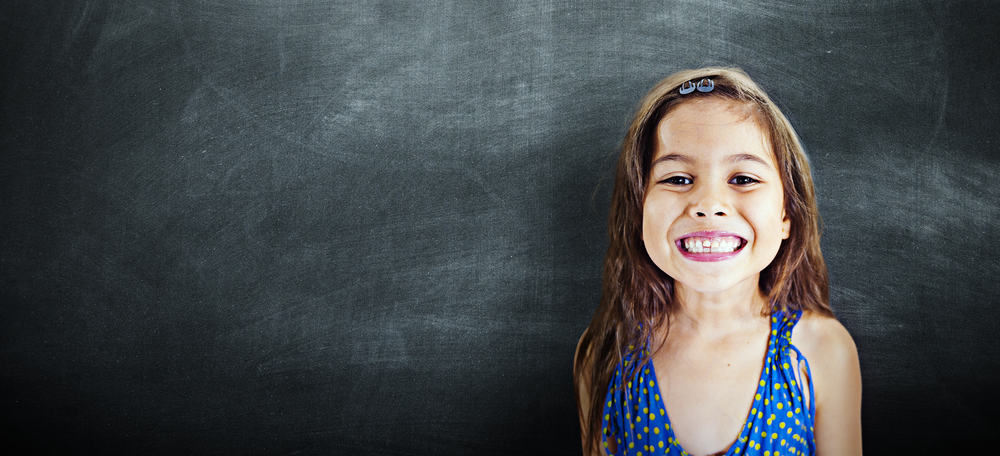 Niña de primaria alegre delante de pizarrón